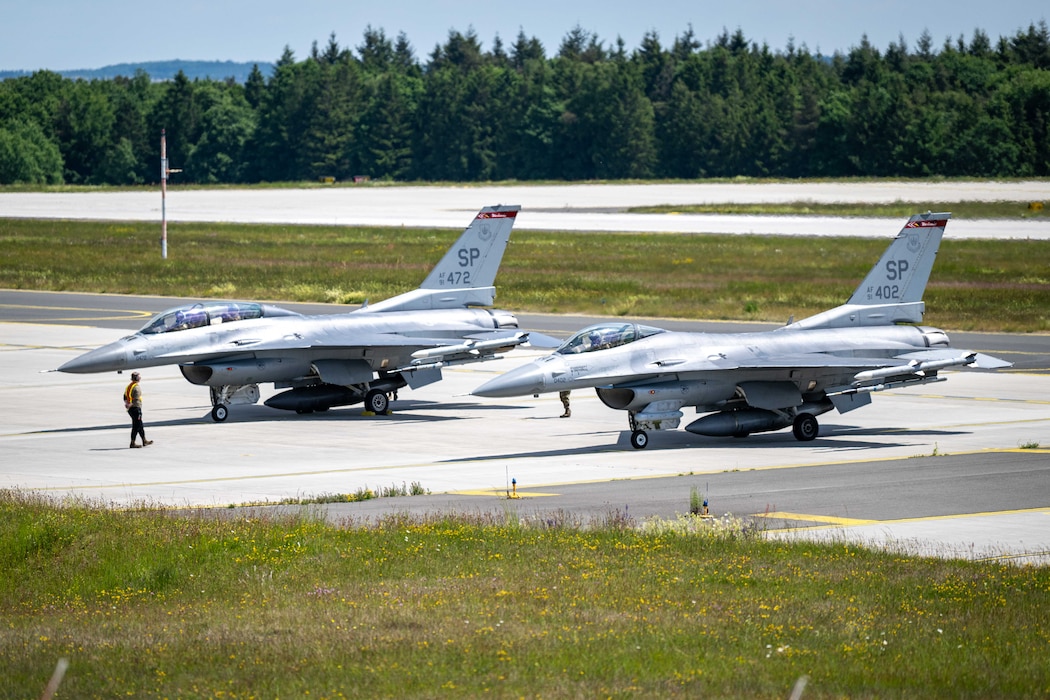 Two fighter aircraft prepare to takeoff on the flightline.