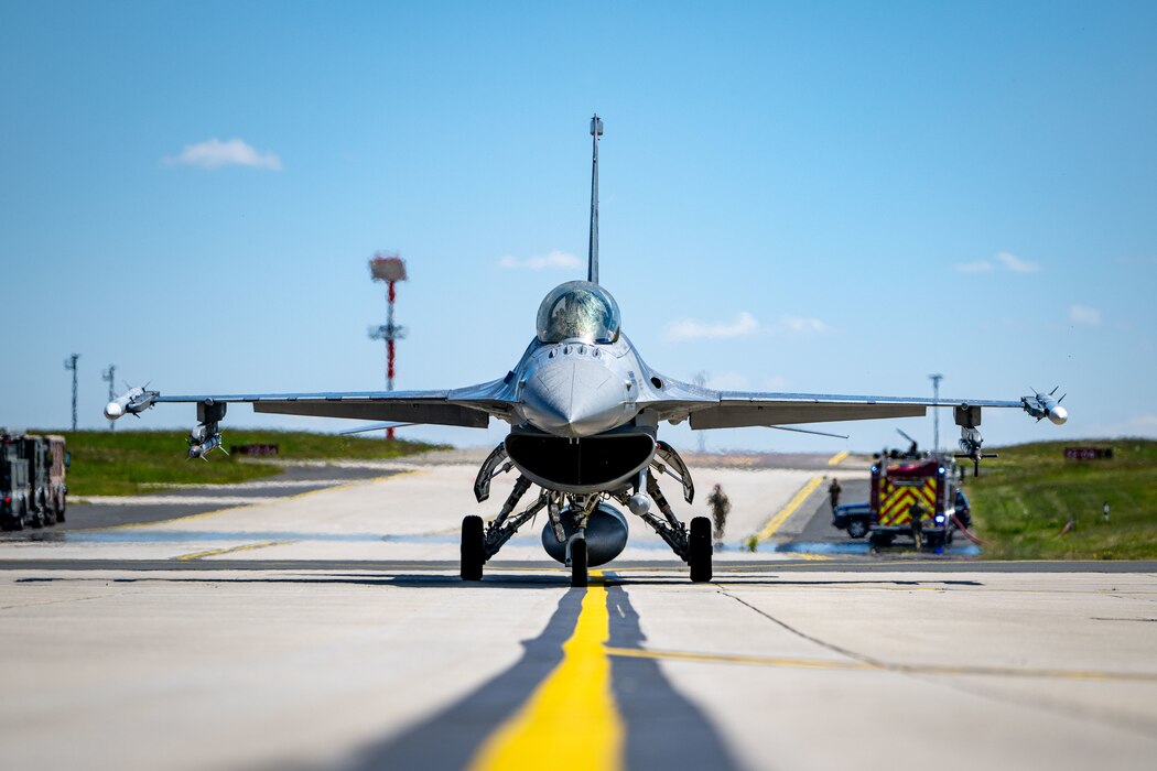 A fighter aircraft taxies along a yellow centerline on the flightline.