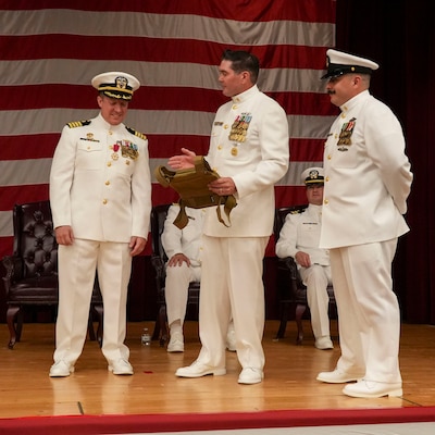 250609-O-NJ594-1012, Portsmouth, Virginia, (June 6, 2025) Command Master Chief Francesco Maccarelli, Command Master Chief of the Navy and Marine Corps Health Protection Command (NMCFHPC), center, and Chief Eric Garcia, a biomedical technician with the NMCFHPC, right, presents Capt. Marion Gregg, outgoing commander of NMCFHPC, former director of Defense Centers for Public Health Portsmouth (DCPH-P), left, with a gift on behalf of the enlisted corps during a change of command ceremony held on board Hampton Roads - Portsmouth Annex, June 6, 2025. Gregg will be transfer to U.S. Naval Forces Central Command (COMUSNAVCENT) where he will serve as the Fifth Fleet Force Surgeon. (U.S. Navy photo by Desmond Martin)