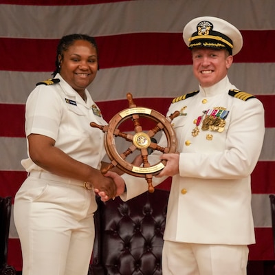 250609-O-NJ594-1013, Portsmouth, Virginia, (June 6, 2025) Lt. Cmdr. Niesha Townsend, associate director of administration assigned to the Navy and Marine Corps Force Health Protection Command (NMCFHPC), left, presents Capt. Marion Gregg, outgoing commander of NMCFHPC, former director of Defense Centers for Public Health Portsmouth (DCPH-P), right, with a gift on behalf of the Ward Room during a change of command ceremony held on board Hampton Roads - Portsmouth Annex, June 6, 2025. A change of command is a time-honored military tradition that signifies the formal transfer of authority, responsibility, and accountability from one leader to another. Gregg will be transfer to U.S. Naval Forces Central Command (COMUSNAVCENT) where he will serve as the Fifth Fleet Force Surgeon. (U.S. Navy photo by Desmond Martin)