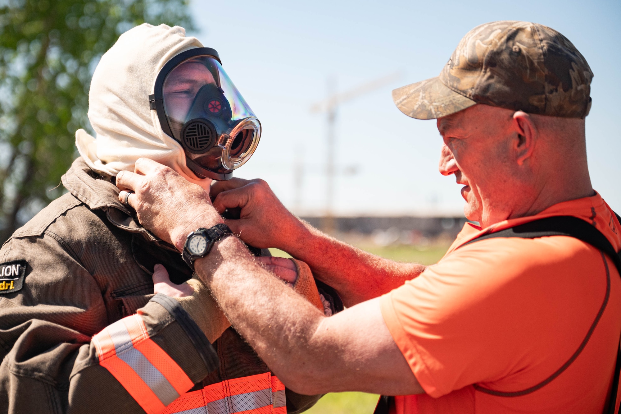 Man helping firefighter suit up