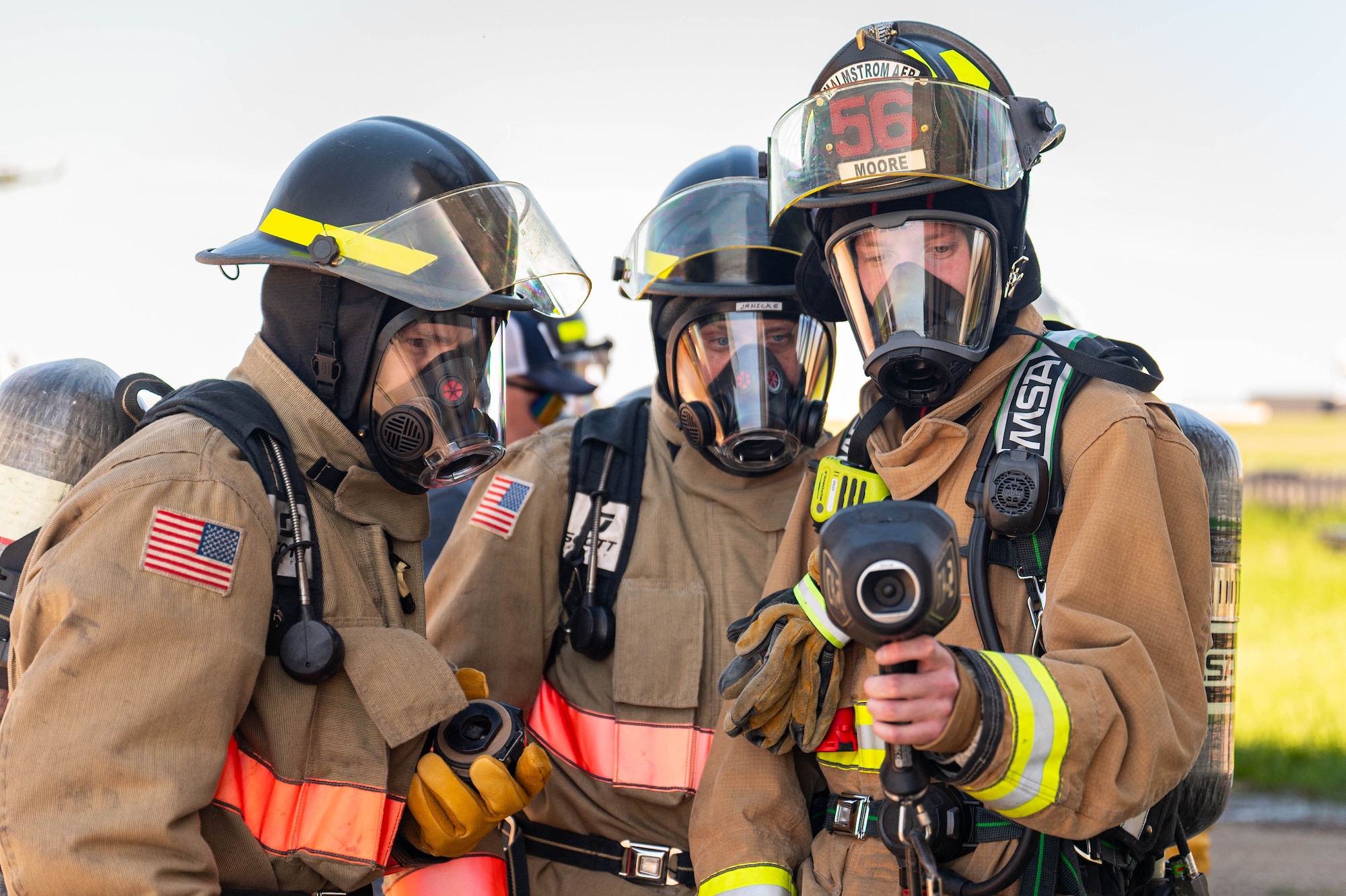 Three firefighters looking at a thermal imaging camera