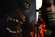 Firefighter ignites a pile of kindling inside a structure