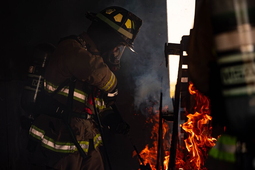 Firefighter ignites a pile of kindling inside a structure
