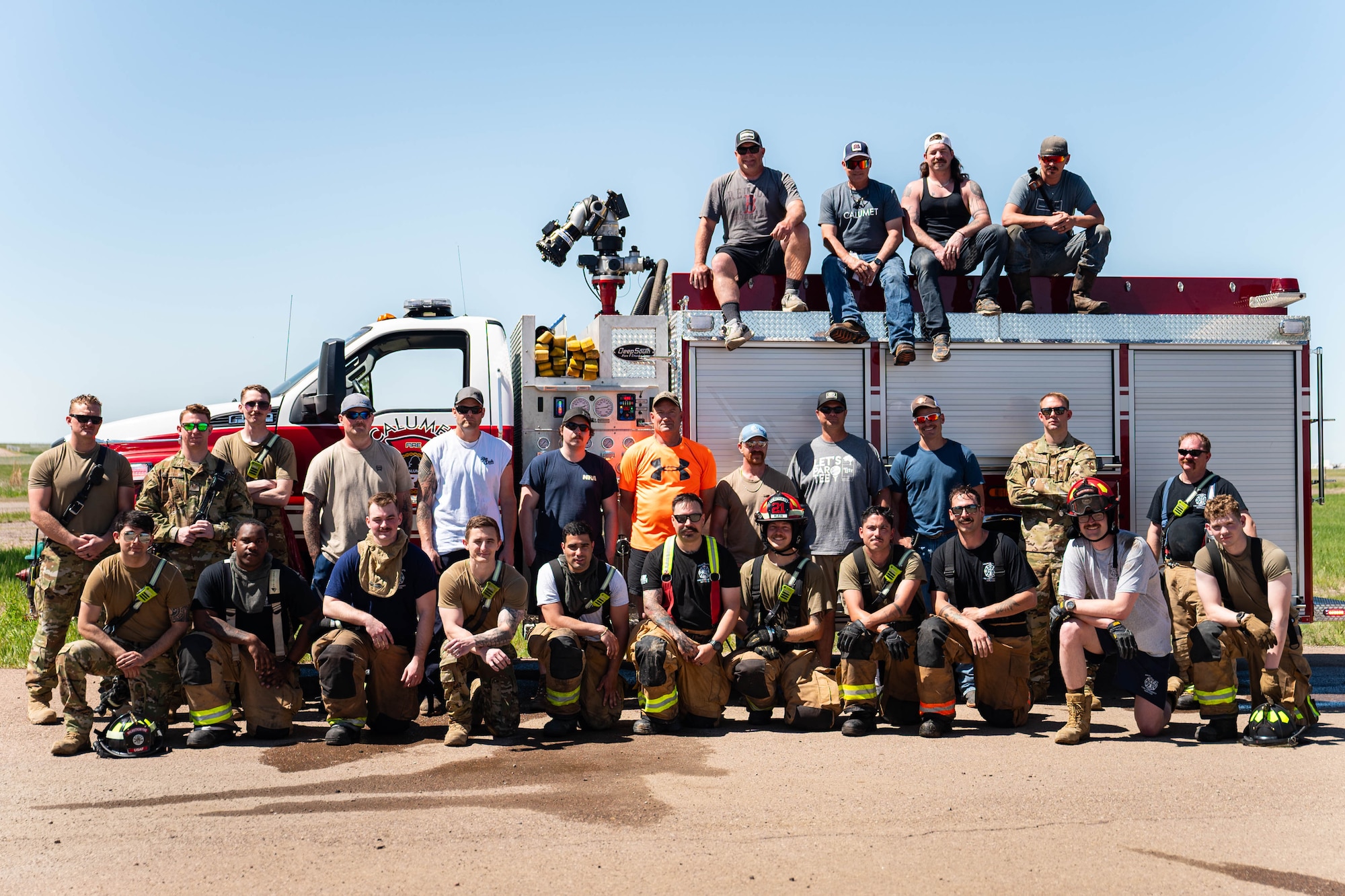 A group of people pose on the side of a firetruck