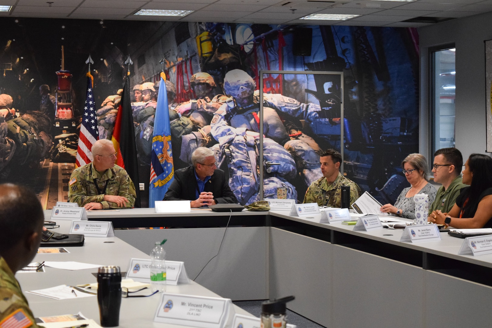 A group of people sit around a large conference table speaking to each other.