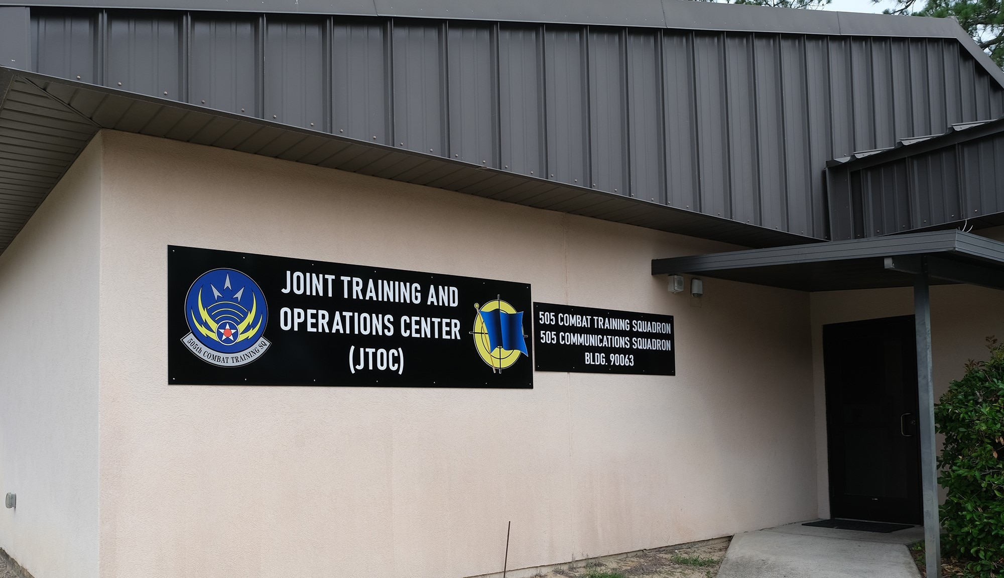 photo of a building with brown signs that have wording “Joint Training and Operations Center (JTOC) and 505th Combat Training Squadron and 505th Communications Squadron”