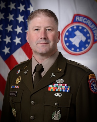 Command photo of male officer posed in front of U.S. flag and USAREC flag.