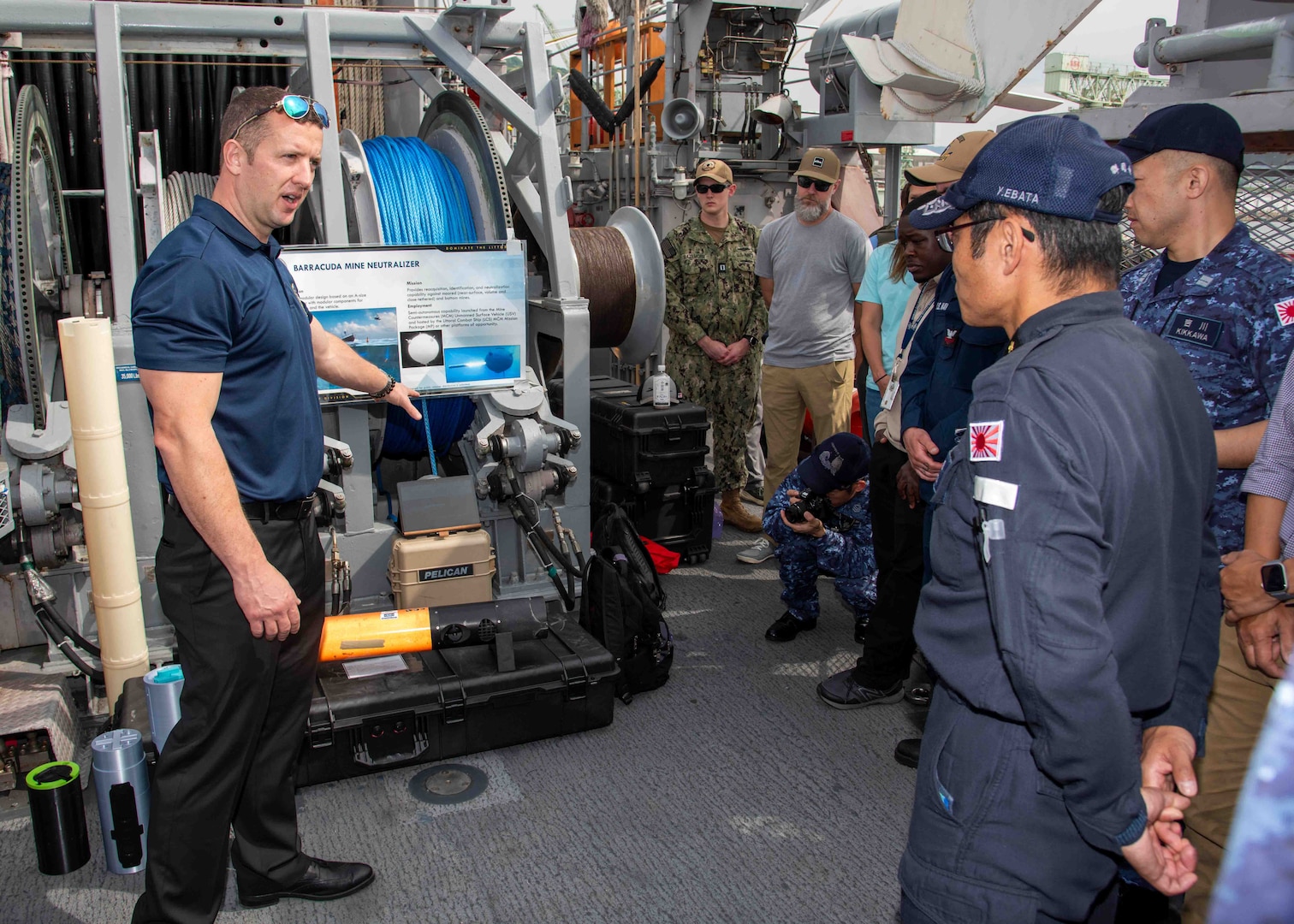 Nate Waldstein, a member of Naval Surface Warfare Center Panama City Division, describes the capabilities of the Barracuda Mine Neutralization System to Japan Maritime Self-Defense Force Rear Adm. Yatsutaka Ebata, commander, Escort Flotilla 2, and Capt. Antonio Hyde, commodore, Mine Countermeasures Squadron 7, during the Integrated Battle Problem 25.5 technology demonstration aboard the Avenger-class mine countermeasures ship USS Warrior (MCM 10), at Commander, Fleet Activities Sasebo, Japan, May 15, 2025. Exercises such as Integrated Battle Problem allow the Navy to demonstrate unmanned system operations in relevant experiment scenarios in order to meet service level objectives and operationalize unmanned systems and capabilities to maintain a secure and prosperous Indo-Pacific region. U.S. 7th Fleet, the U.S. Navy’s largest forward-deployed numbered fleet, routinely interacts and operates with allies and partners in preserving a free and open Indo-Pacific region. (U.S. Navy photo by Mass Communication Specialist 1st Class W. Chase Stephens)