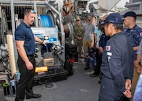 Nate Waldstein, a member of Naval Surface Warfare Center Panama City Division, describes the capabilities of the Barracuda Mine Neutralization System to Japan Maritime Self-Defense Force Rear Adm. Yatsutaka Ebata, commander, Escort Flotilla 2, and Capt. Antonio Hyde, commodore, Mine Countermeasures Squadron 7, during the Integrated Battle Problem 25.5 technology demonstration aboard the Avenger-class mine countermeasures ship USS Warrior (MCM 10), at Commander, Fleet Activities Sasebo, Japan, May 15, 2025. Exercises such as Integrated Battle Problem allow the Navy to demonstrate unmanned system operations in relevant experiment scenarios in order to meet service level objectives and operationalize unmanned systems and capabilities to maintain a secure and prosperous Indo-Pacific region. U.S. 7th Fleet, the U.S. Navy’s largest forward-deployed numbered fleet, routinely interacts and operates with allies and partners in preserving a free and open Indo-Pacific region. (U.S. Navy photo by Mass Communication Specialist 1st Class W. Chase Stephens)