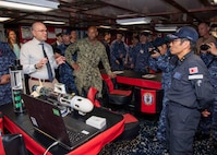 Christian Weber, the Integrated Battle Problem 25.5 technology lead from Naval Surface Warfare Center Panama City Division, describes the capabilities of the Disposable Reusable Expeditionary Warfare Underwater Vehicle (DREW-UV) to Japan Maritime Self-Defense Force Rear Adm. Yatsutaka Ebata, commander, Escort Flotilla 2, and Capt. Antonio Hyde, commodore, Mine Countermeasures Squadron 7, during the Integrated Battle Problem 25.5 technology demonstration aboard the Avenger-class mine countermeasures ship USS Warrior (MCM 10), at Fleet Activities Sasebo, Japan, May 15, 2025. Exercises such as Integrated Battle Problem allow the Navy to demonstrate unmanned system operations in relevant experiment scenarios to meet service level objectives and operationalize unmanned systems and capabilities to maintain a secure and prosperous Indo-Pacific region. U.S. 7th Fleet, the U.S. Navy’s largest forward-deployed numbered fleet routinely interacts and operates with allies and partners in preserving a free and open Indo-Pacific region. (U.S. Navy photo by Mass Communication Specialist 1st Class W. Chase Stephens. Portions of this photo have been obscured for security purposes.)