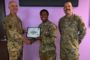 U.S. Air Force Col. Jeff Marshall, 97th Air Mobility Wing (AMW) commander, left, and Chief Master Sgt. Justin Brundage, 97th AMW command chief, right, presents the Airman of the Month award to Airman 1st Class Christopher Platt, 97th Force Support Squadron (FSS) force management technician, at Altus Air Force Base, Oklahoma, May 29, 2025. The 97th FSS mission is to enhance the quality of life for service members, DoD civilians, retirees, and families. (U.S. Air Force photo by Airman 1st Class Nathan Langston)