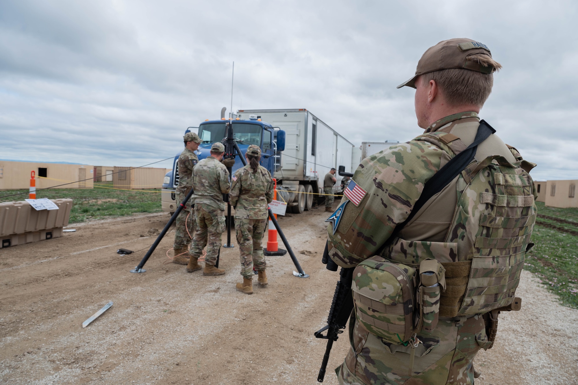 A Guardian stands guard as fellow team members set up a mobile constellation control station lightning protection system.