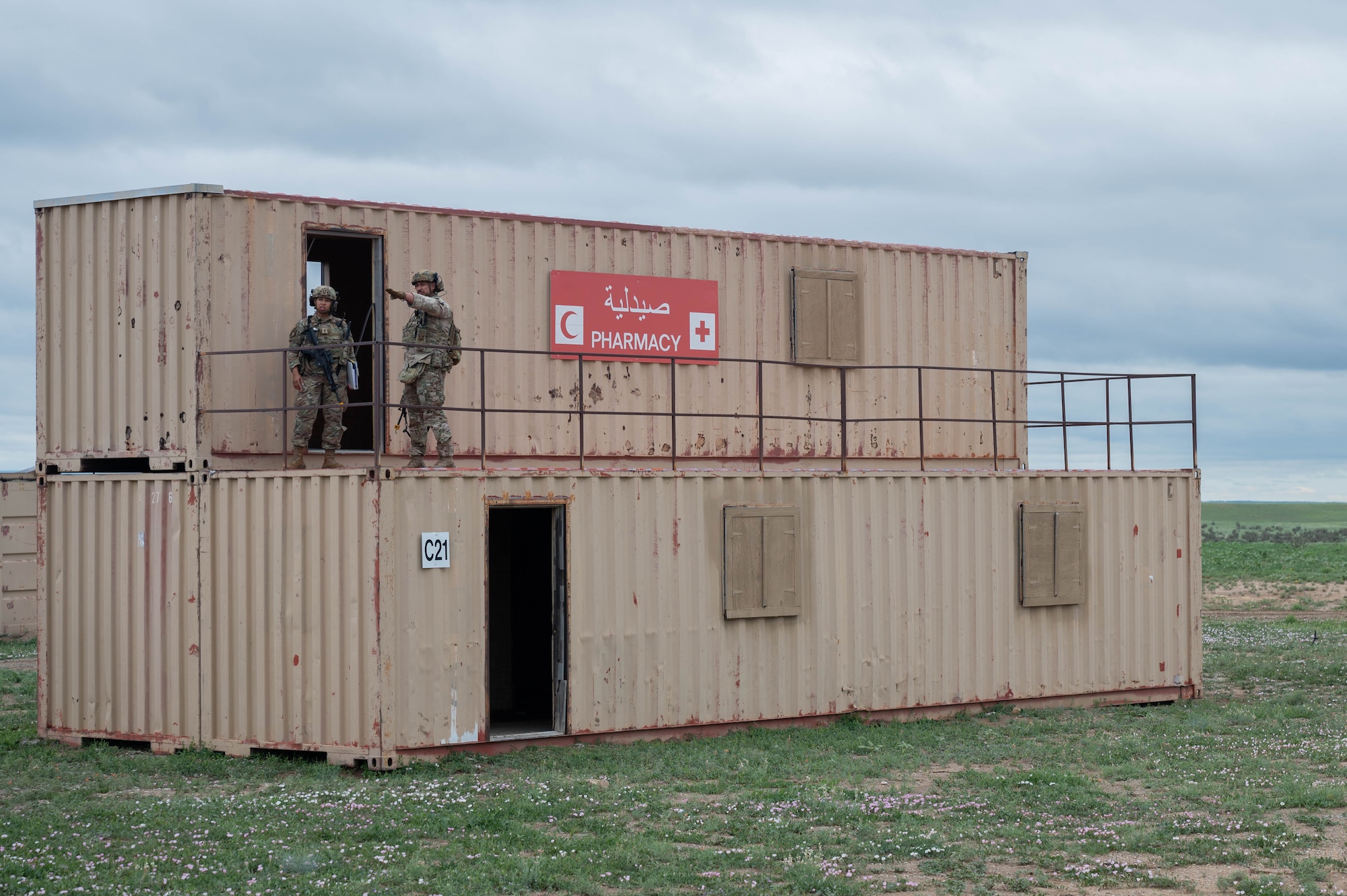 Two security forces members talk while standing atop of a conex box.