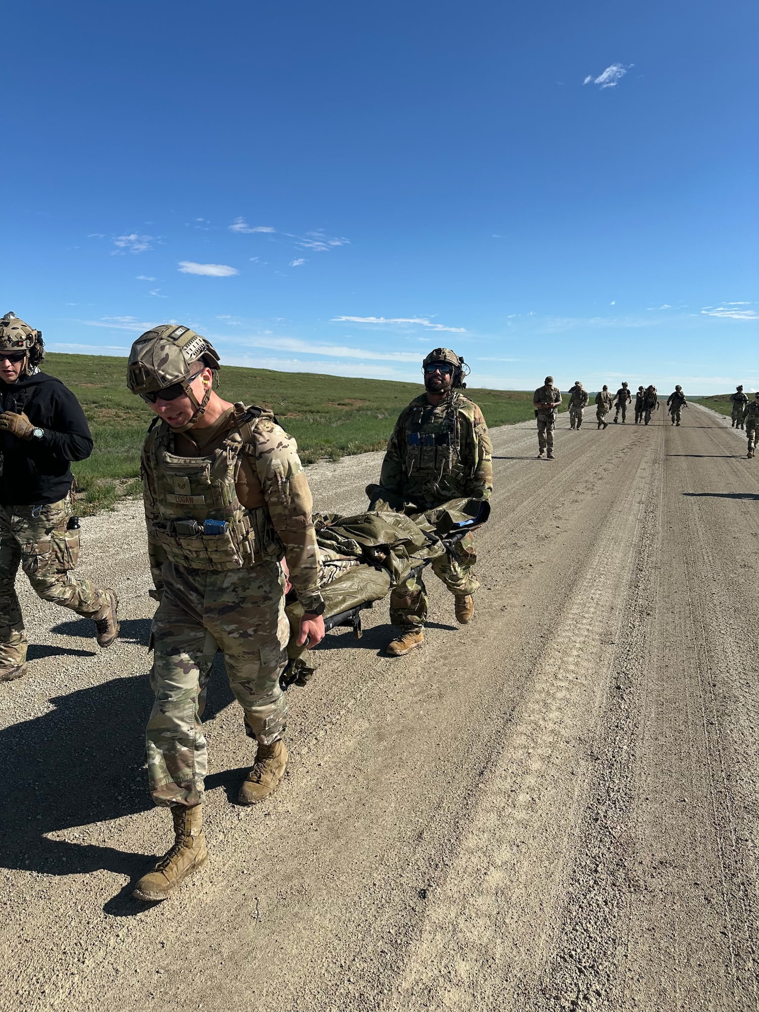 Security forces members carry a fellow teammate on a stretcher during an exercise.