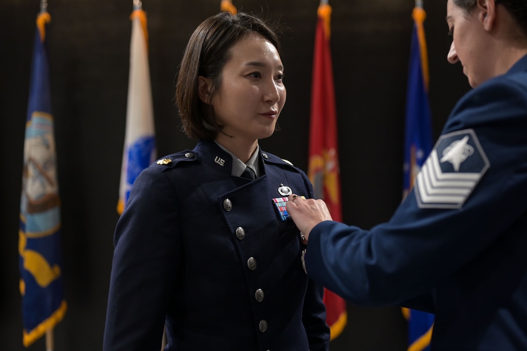 U.S. Space Force Tech. Sgt. Christina Epperson pins Maj. Uiri Han’s commander pin on her service coat during the 533rd TRS, Detachment 1 Change of Command Ceremony at the Powell Event Center, Goodfellow Air Force Base, Texas, June 10, 2025. In keeping with a military tradition dating back to 18th-century Prussia, the 533rd TRS Detachment 1 Change of Command ceremony was officiated by Lt. Col. Adam P. Jodice, who received the guidon from Tillman before passing it to Han, signifying the formal transition of leadership. (U.S. Air Force photo by Senior Airman Evelyn J. D’Errico)