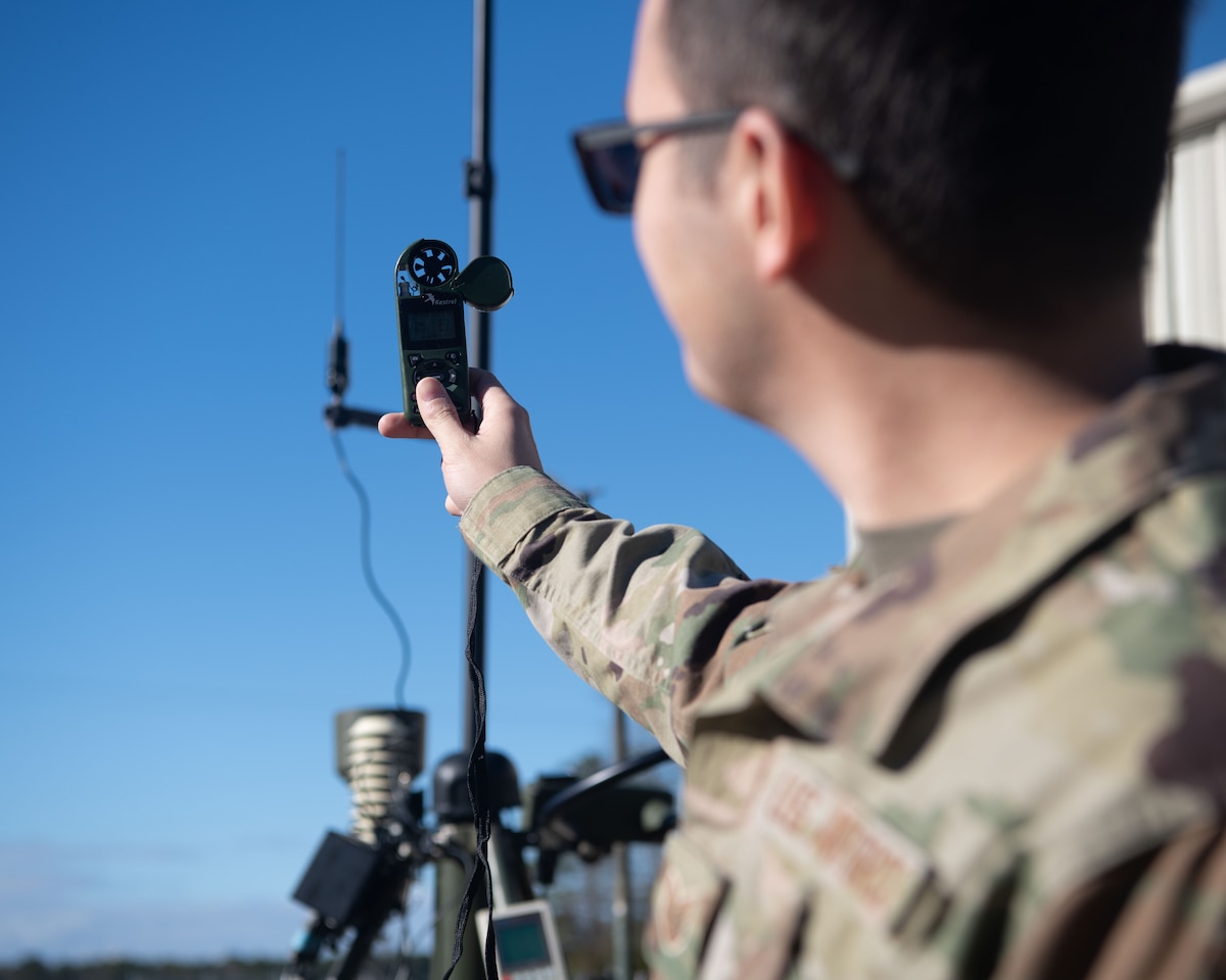 Airman holds up weather equipment to the sky