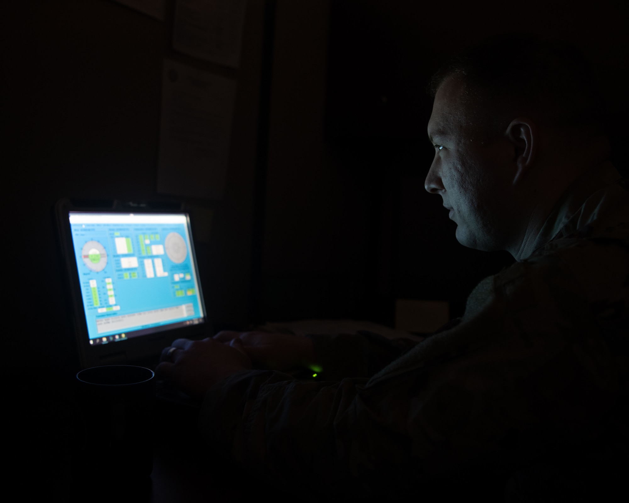 Airman sitting in dark room looking at computer screen