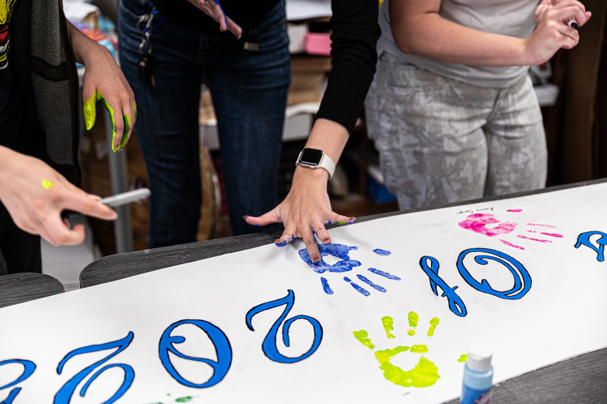 students signing a banner with hand paint