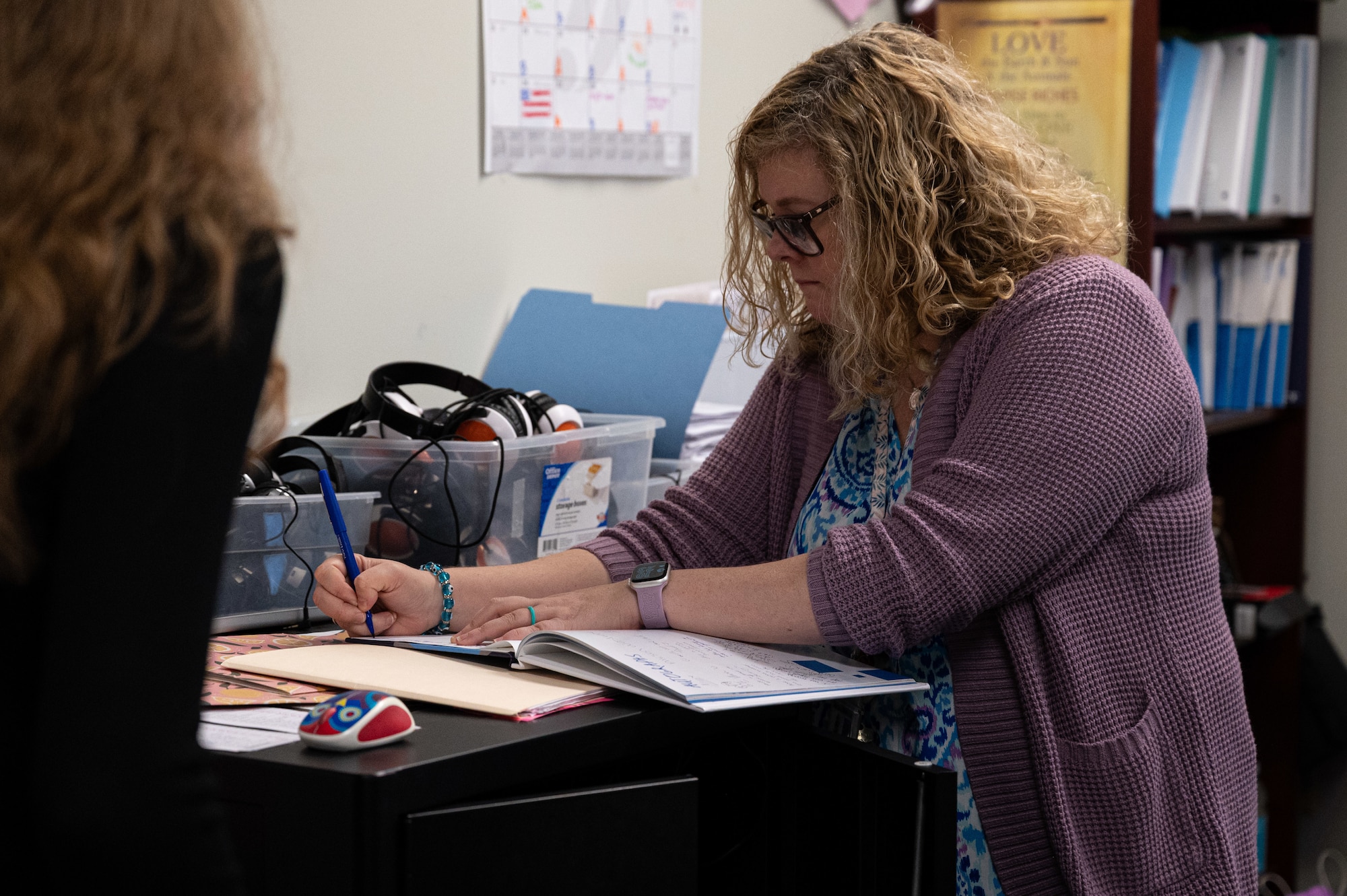 A lady writing in a book at a school