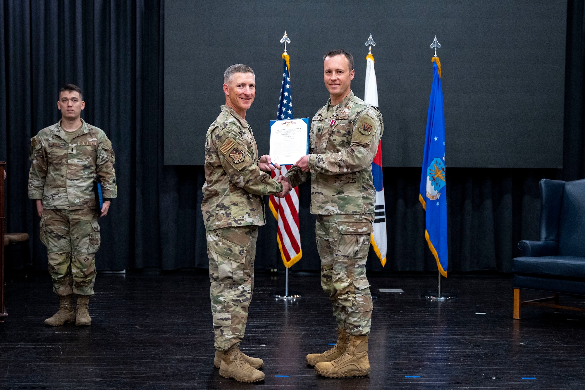 U.S. Air Force Lt. Col. Adam Fossum, outgoing 6th Intelligence Squadron commander, right, receives the Meritorious Service Medal from Col. Douglas Mabry, 694th Intelligence, Surveillance and Reconnaissance Group commander, during a Change of Command ceremony at Osan Air Base, Republic of Korea, June 11, 2025.
