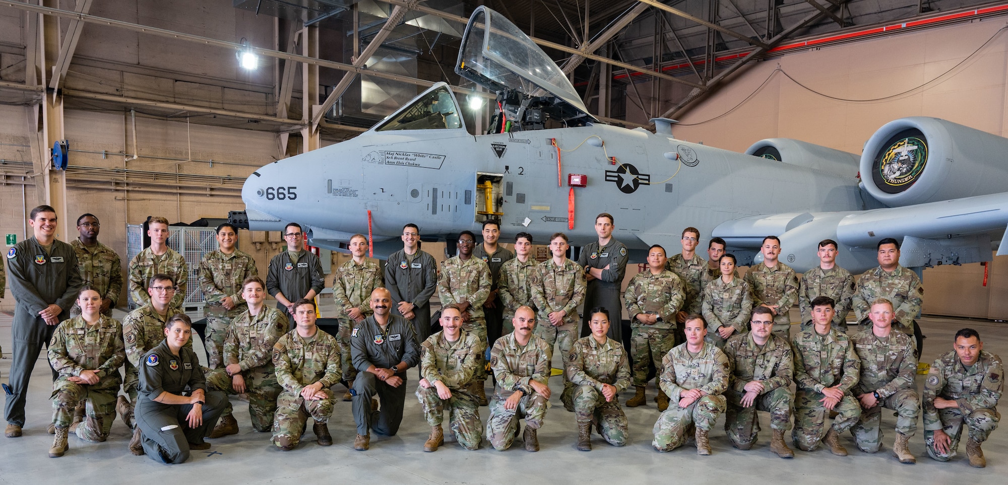 Airmen posing in front of an airplane.