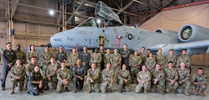 Airmen posing in front of an airplane.