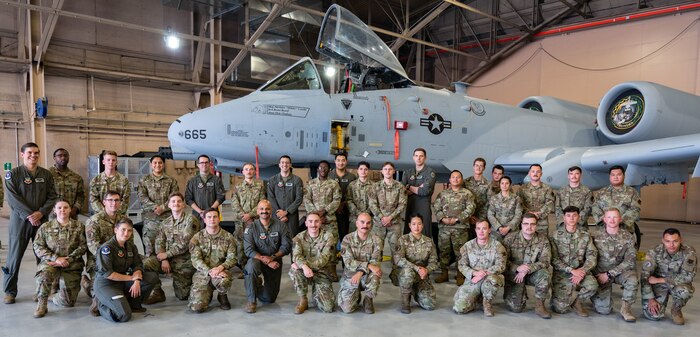 Airmen posing in front of an airplane.