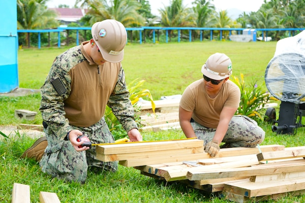 Builder 2nd Class Brian Porter, left, and Utilitiesman Constructionman Marces Butackahawai, both assigned to Amphibious Construction Battalion 1, prepare lumber for the Waiqanake School library construction project, during Pacific Partnership 2025, in Suva, Fiji, June 9, 2025