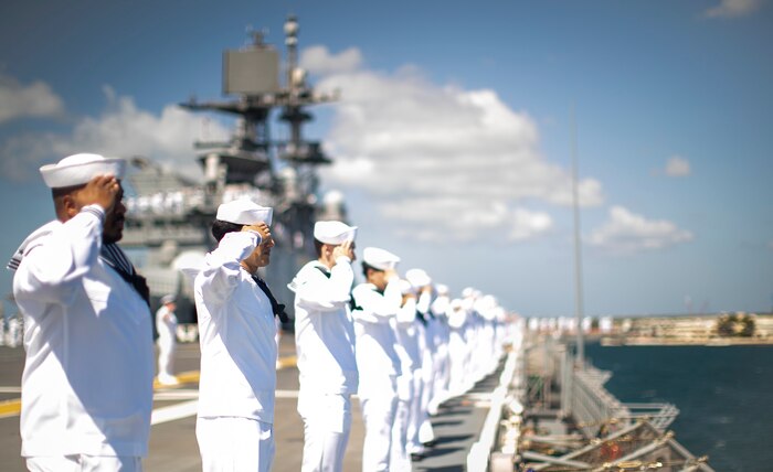 Sailors man the rails aboard amphibious assault carrier USS Tripoli (LHA 7), as the ship pulls into Pearl Harbor, Hawaii, June 6, 2025.