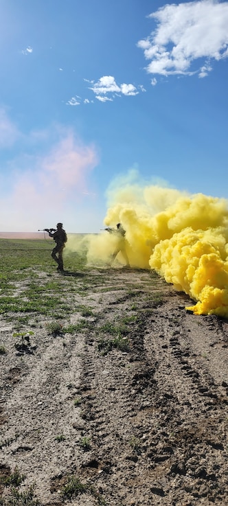  Security forces members walk through a cloud of yellow smoke while participating in an exercise.
