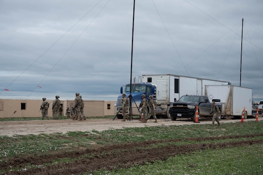 Image of security forces members walking around vehicles and securing an area during an exercise.