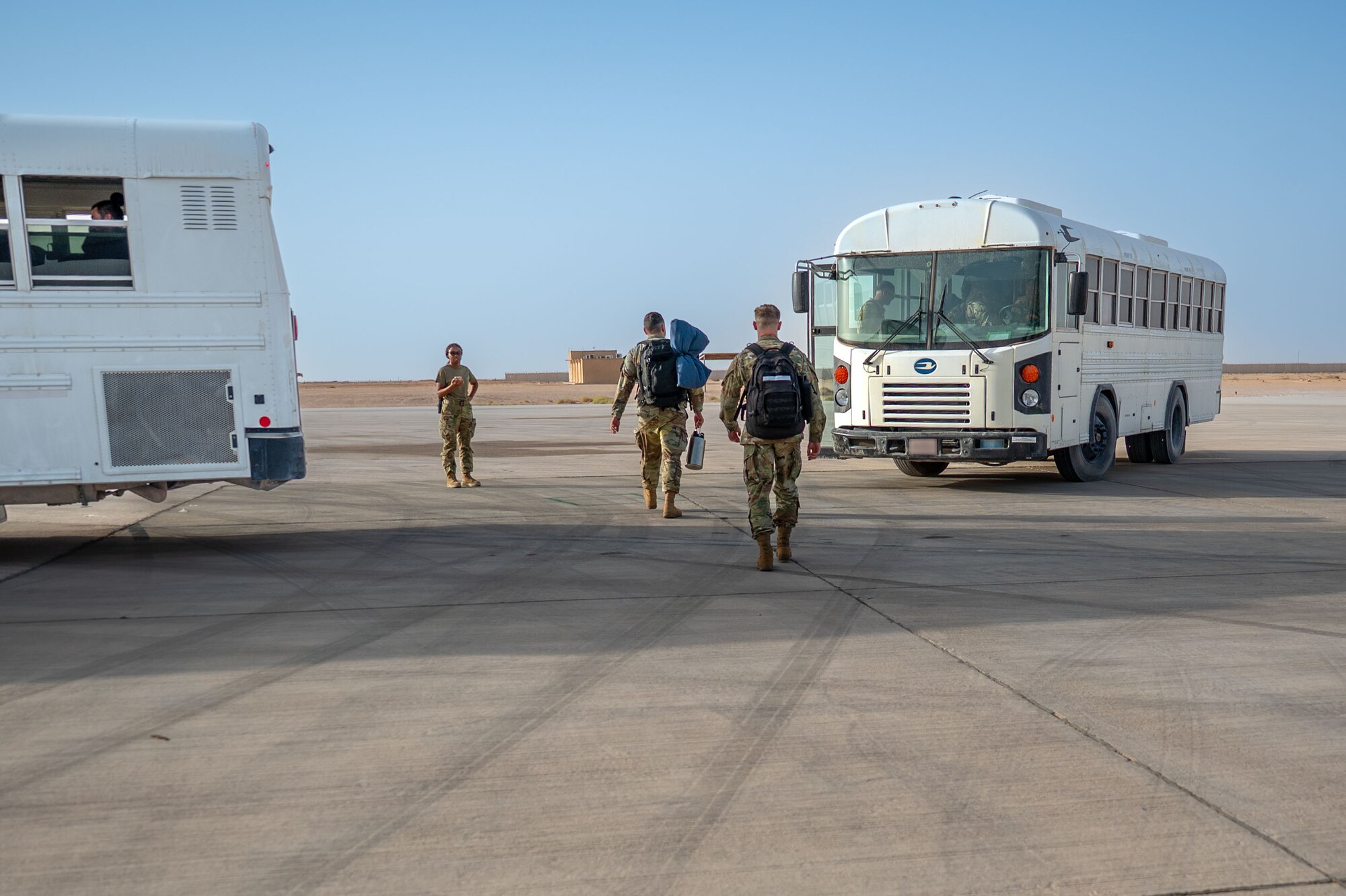 Airmen walk toward a bus.
