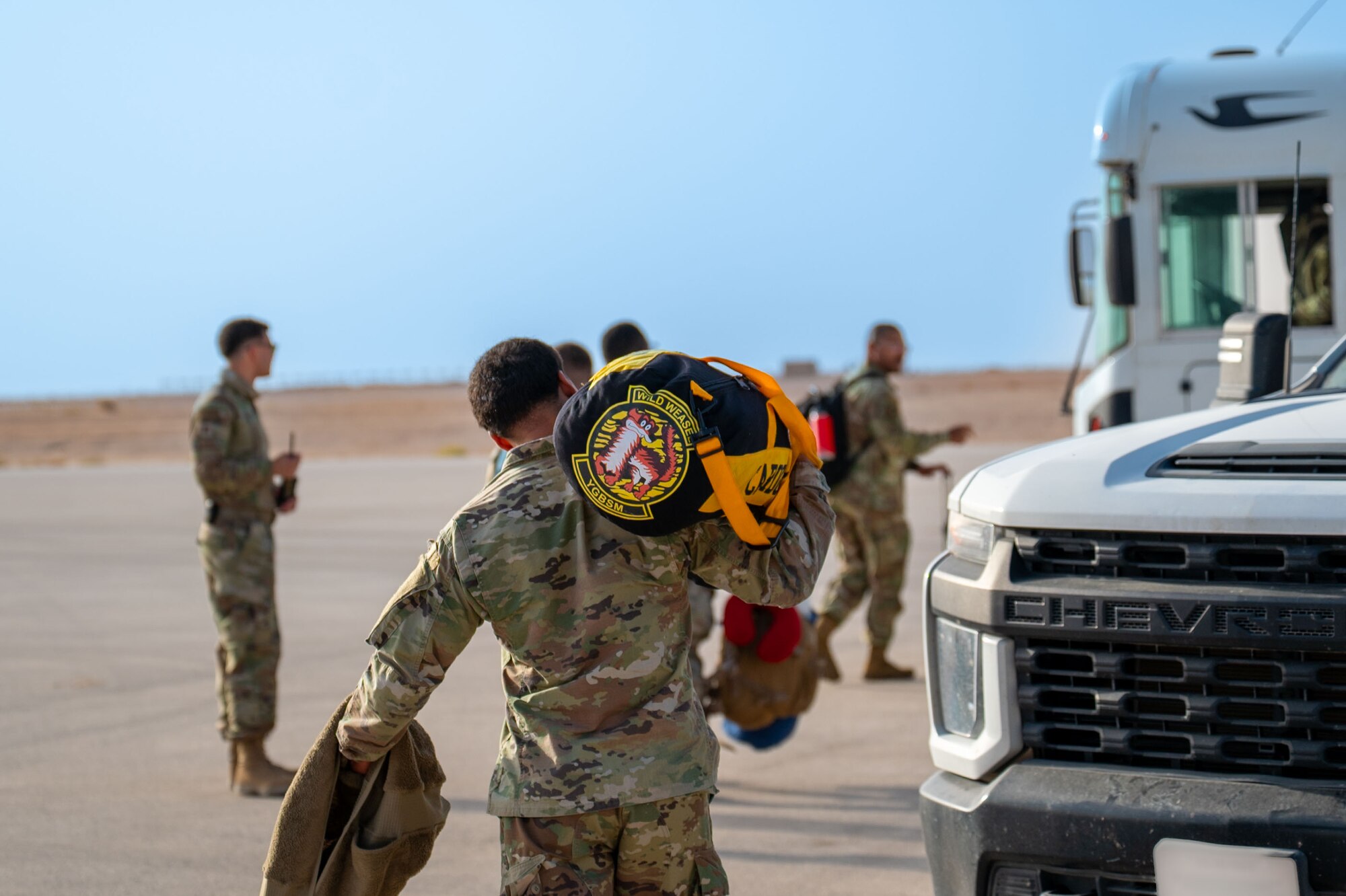 An Airman carrying a bag walks toward a bus.