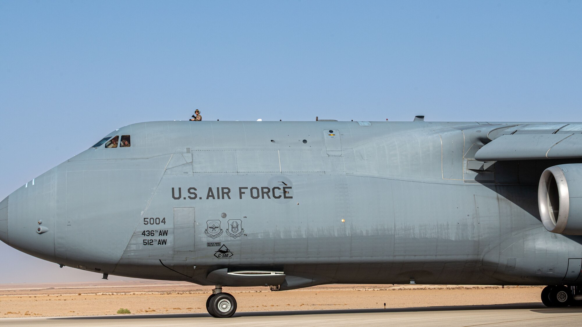 An Airmen poses for a photo from the top hatch of a C-5M.