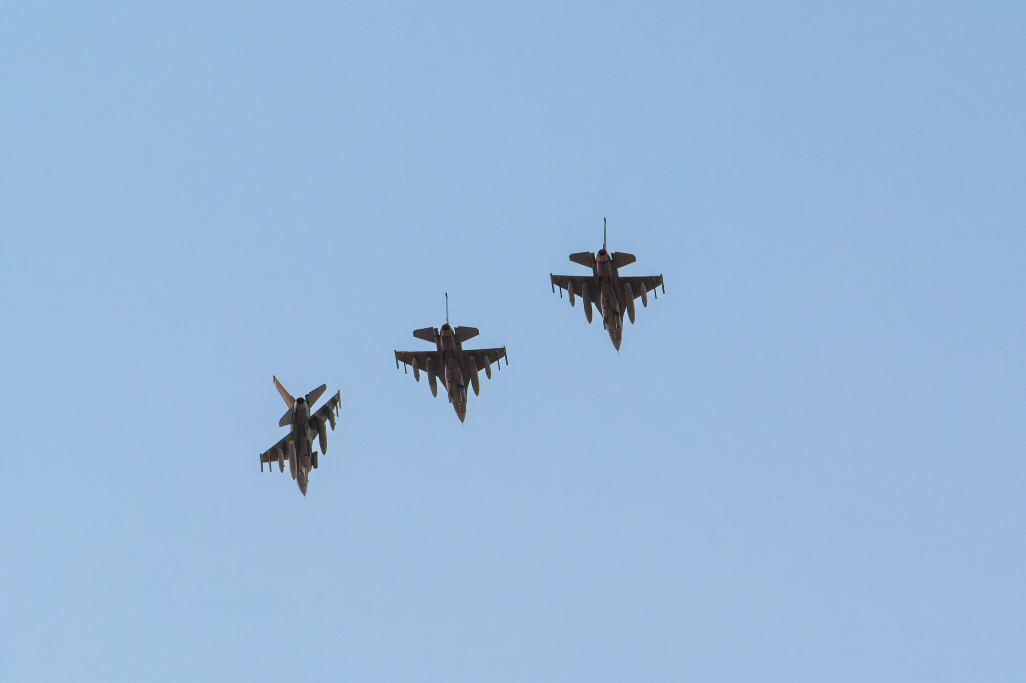 Three F-16C Fighting Falcons fly overhead.