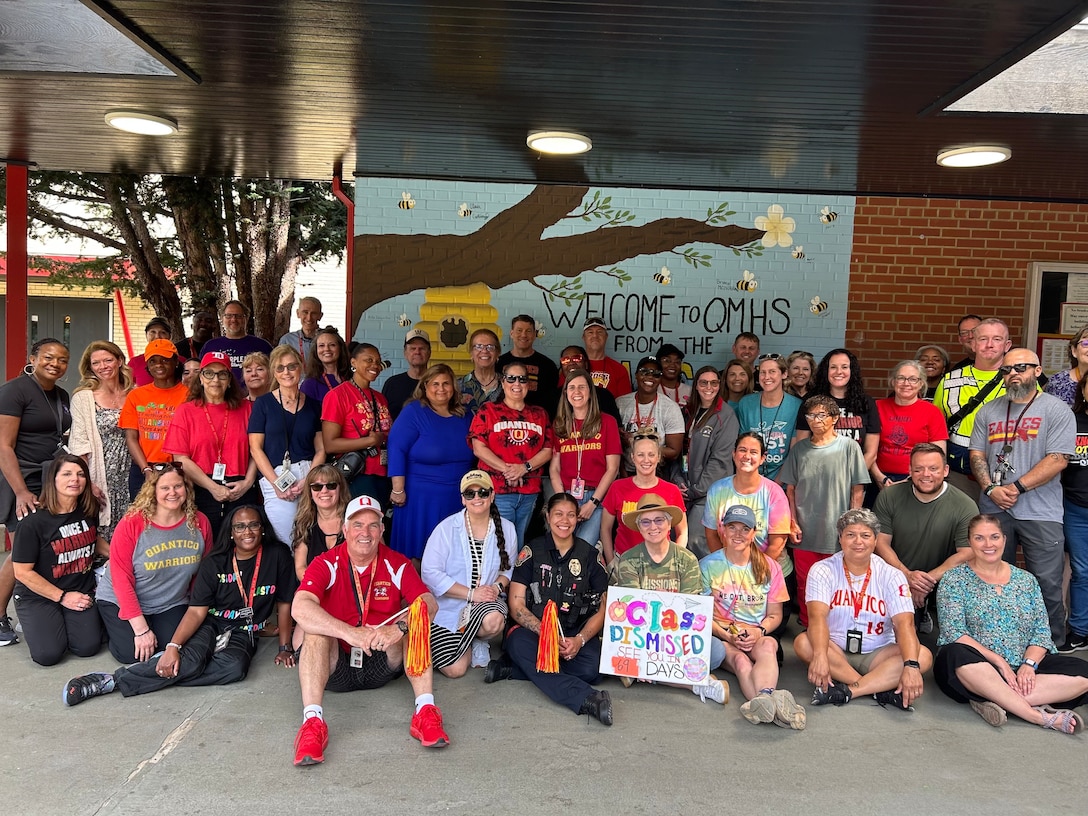 Miles Shea (seated wearing red shirt and a white hat), the Quantico Middle High School principal, and QMHS staff take one last photo as the 2024-2025 school year comes to an end, June 10, 2025. Shea was awarded the DoD Education Activity Americas’ 2025 Principal of the Year for his service and dedication to military-connected students. The DoDEA Principal of the Year Program honors exceptional school principals from three regions: the Americas, Europe, and Pacific regions; each selectee must have demonstrated leadership in creating high-quality learning experiences for students and made significant contributions to the education profession. "I have simply had the opportunity to be a member of that team, and I have been fortunate to accept such a prestigious award on behalf of the entire Marine Corps Base Quantico community.” (Courtesy photo by QMHS staff)