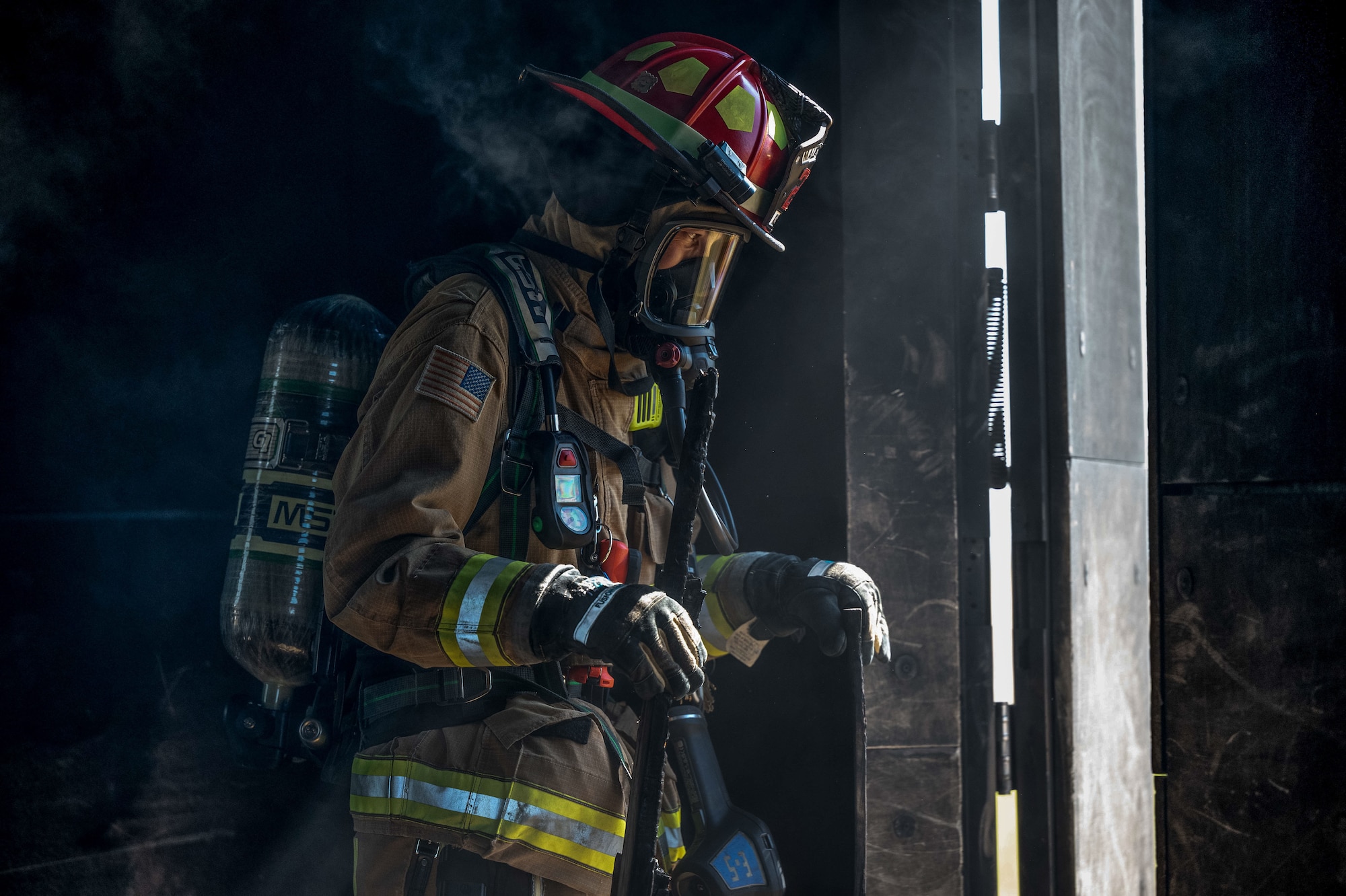 Firefighter walking out of door into sunlight with smoke coming off him