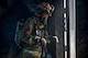 Firefighter walking out of door into sunlight with smoke coming off him