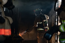 Firefighter ignites a pile of kindling inside a structure
