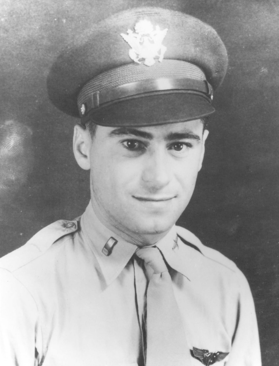 A man in a military dress uniform and cap poses for a photo.
