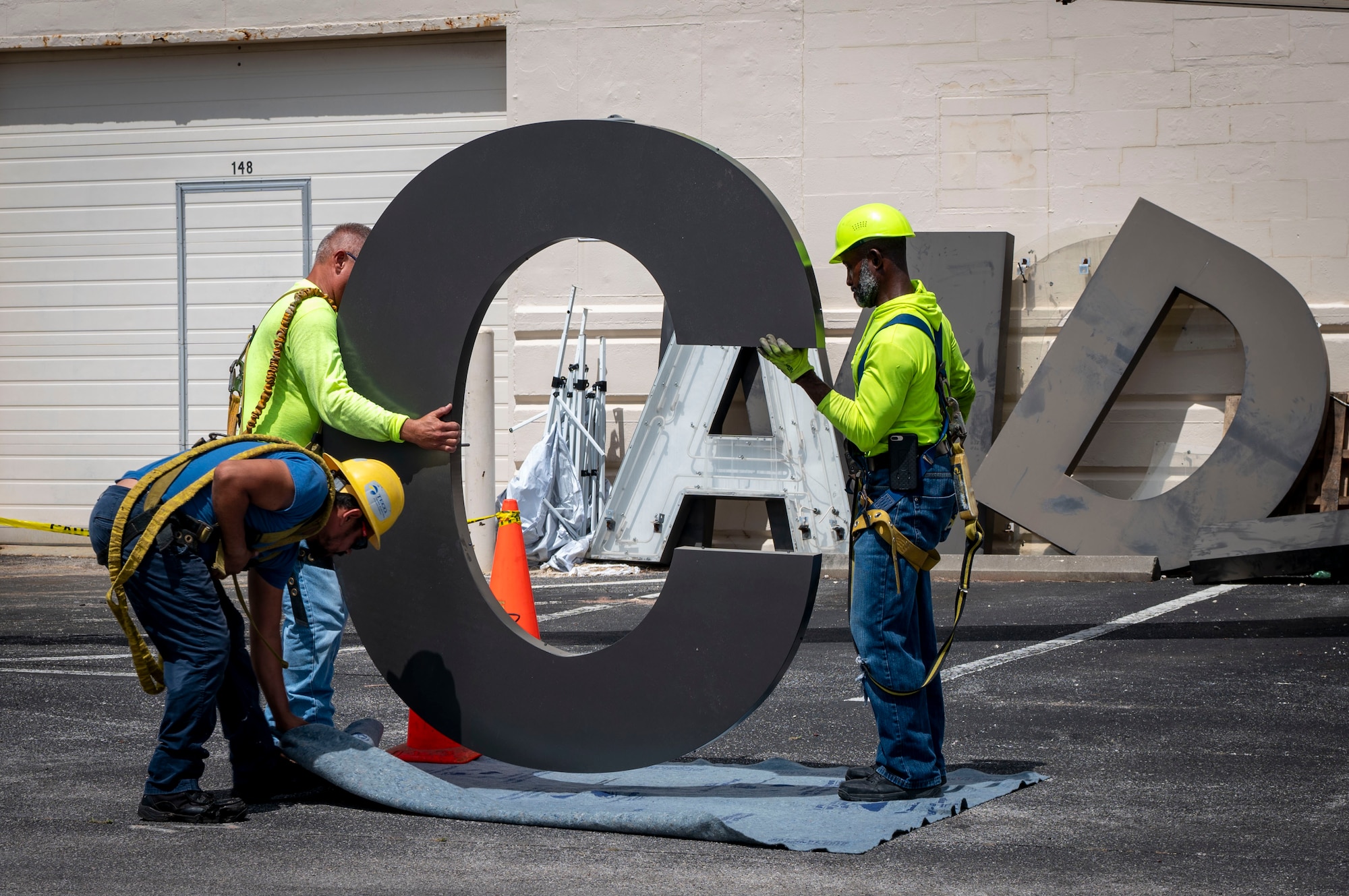 Electricians with Mark One Power prepare to install the letter “C” on Hangar 3 at MacDill Air Force Base, Florida, June 6, 2025. The previous letter was blown off the hangar during Hurricane Helene, a Category 4 hurricane that struck the region in September 2024. Since then, extensive repairs have been completed, with the recent restoration of the iconic MacDill AFB sign symbolizing the base’s recovery from the hurricanes. (U.S. Air Force photo by Airman 1st Class Alicia Campbell)