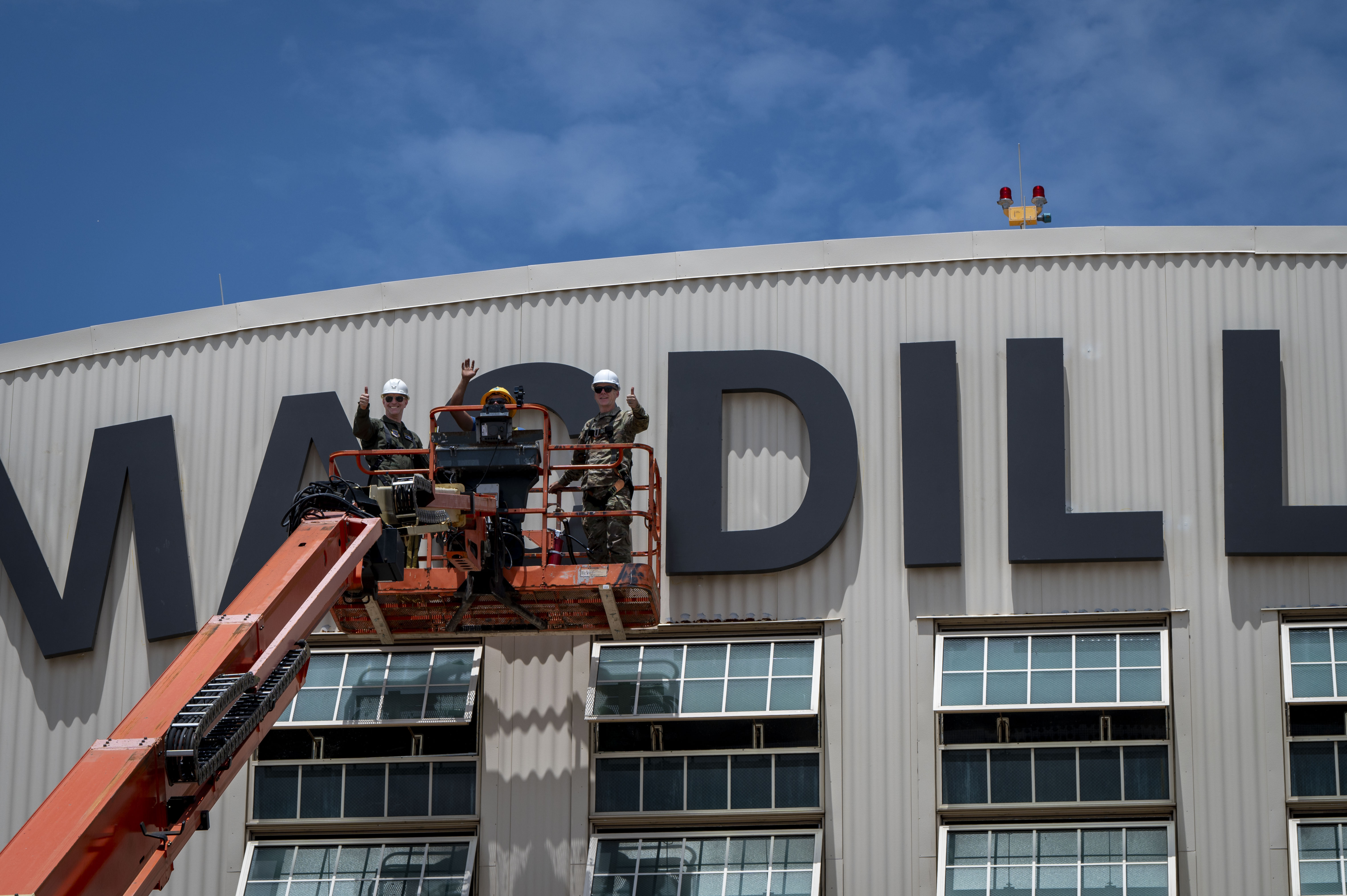 From left, U.S. Air Force Col. Edward Szczepanik, 6th Air Refueling Wing commander, Enrique Gallegos, an electrician with Mark One Power, and Chief Master Sgt. Raun Howell, 6th ARW command chief, wave in front of the MacDill sign during the hanging of the letter “C” on Hangar 3 at MacDill Air Force Base, Florida, June 6, 2025. The previous letter was blown off the hangar during Hurricane Helene, a Category 4 hurricane that struck the region in September 2024. Since then, extensive repairs have been completed, with the recent restoration of the iconic MacDill AFB sign symbolizing the base’s recovery from the hurricanes. (U.S. Air Force photo by Airman 1st Class Alicia Campbell)