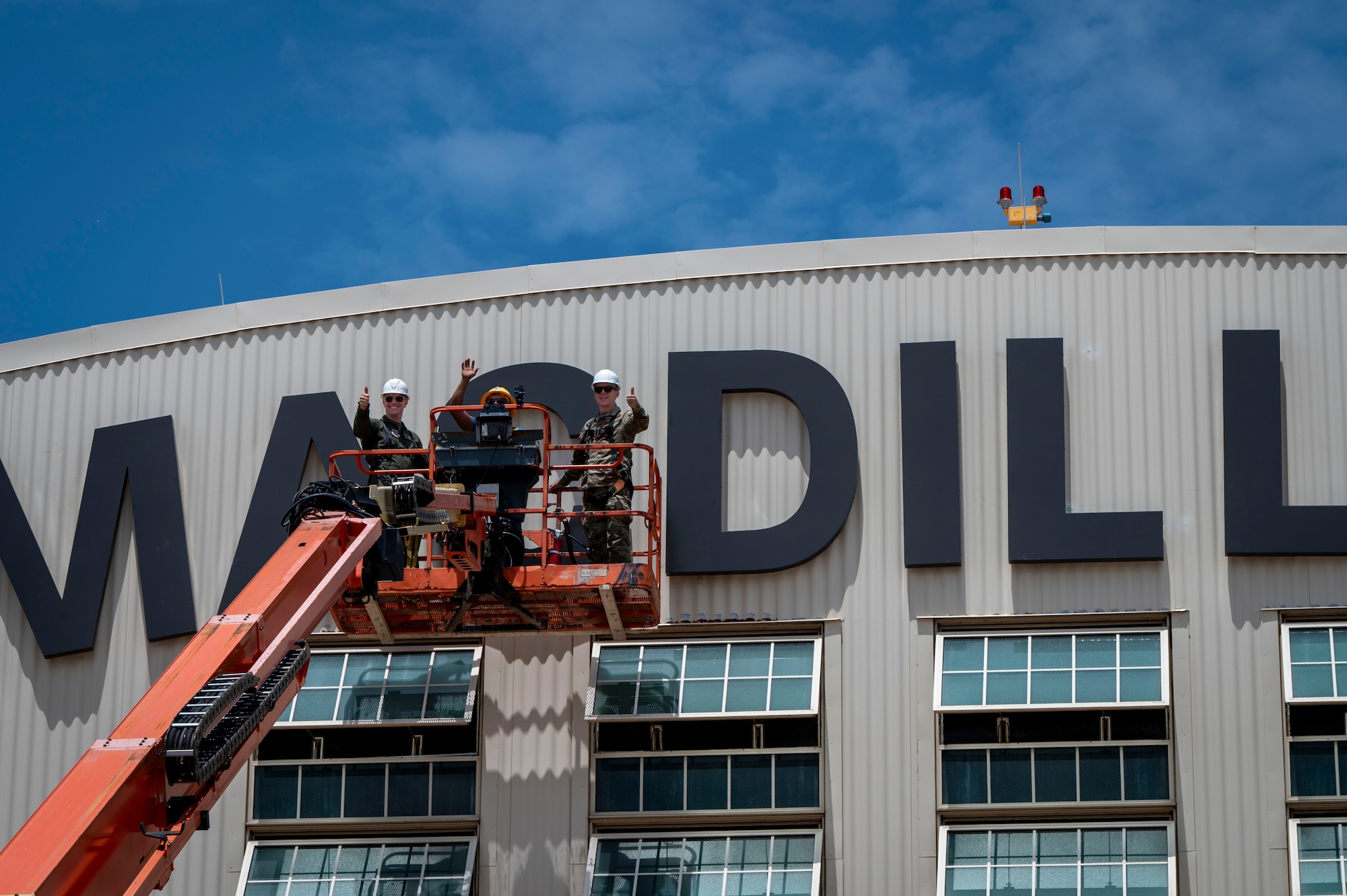 From left, U.S. Air Force Col. Edward Szczepanik, 6th Air Refueling Wing commander, Enrique Gallegos, an electrician with Mark One Power, and Chief Master Sgt. Raun Howell, 6th ARW command chief, wave in front of the MacDill sign during the hanging of the letter “C” on Hangar 3 at MacDill Air Force Base, Florida, June 6, 2025. The previous letter was blown off the hangar during Hurricane Helene, a Category 4 hurricane that struck the region in September 2024. Since then, extensive repairs have been completed, with the recent restoration of the iconic MacDill AFB sign symbolizing the base’s recovery from the hurricanes. (U.S. Air Force photo by Airman 1st Class Alicia Campbell)