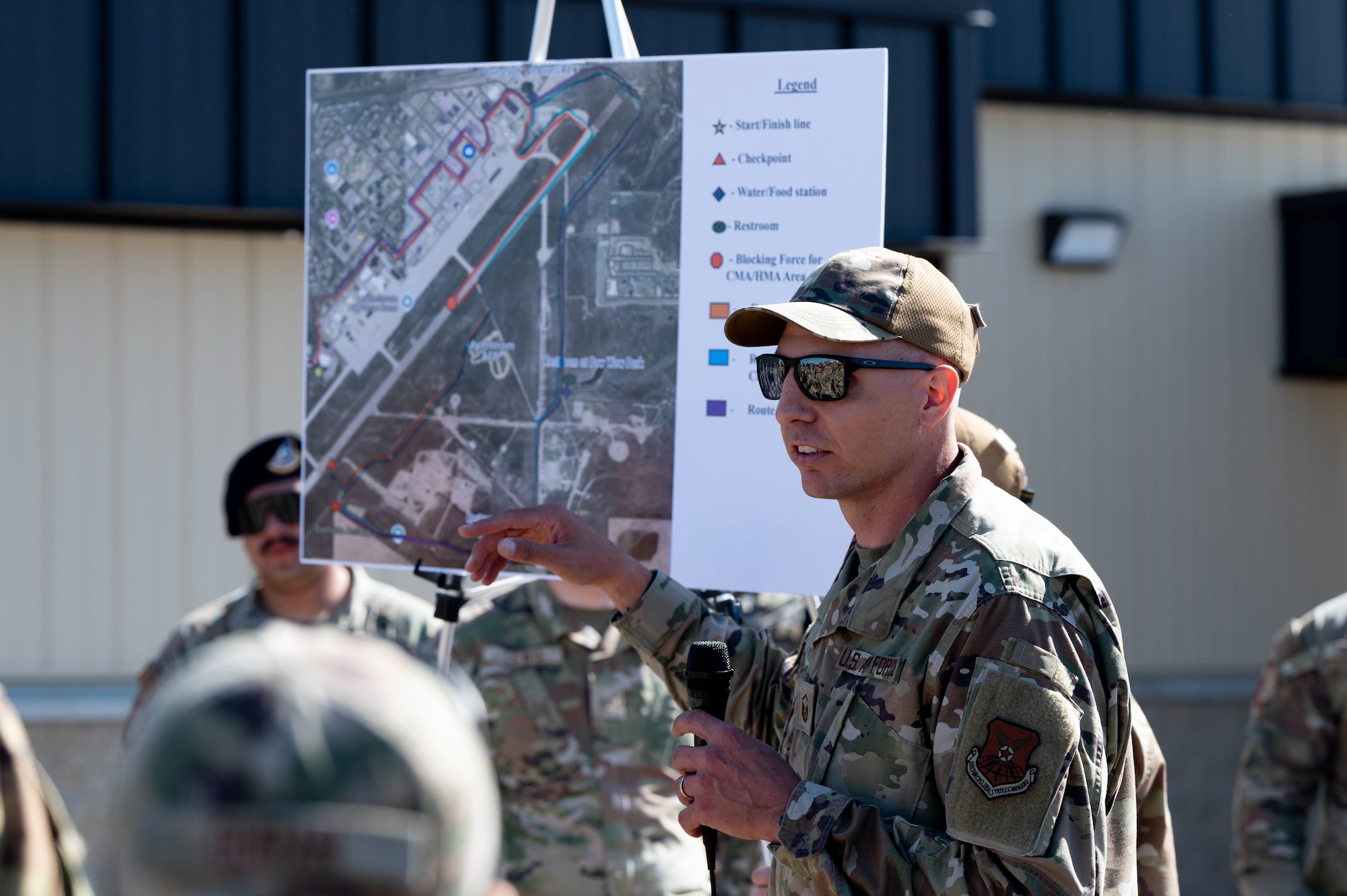 Airman with microphone talking to group around him.