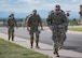 Airmen with ruck sacks running on sidewalk.