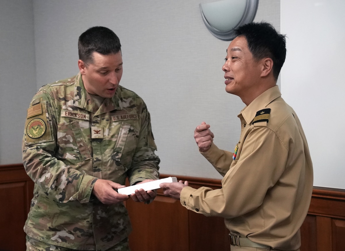 HANSCOM AIR FORCE BASE, Mass., (June 3, 2025) – Col. Ted Erickson, left, and Japan Maritime Self Defense Force Capt. Daigo Tsubokura, exchange gifts before discussing Air Force capabilities, here, June 3, 2025. Delegates from the Japanese Joint Staff met with Airmen to learn more about the Department of the Air Force’s Program Executive Office for Command, Control, Communications and Battle Management’s DAF BATTLE NETWORK. Erickson is C3BM’s Air Mission Integration Team lead. (Official Air Force Photo by Richard Blumenstein)