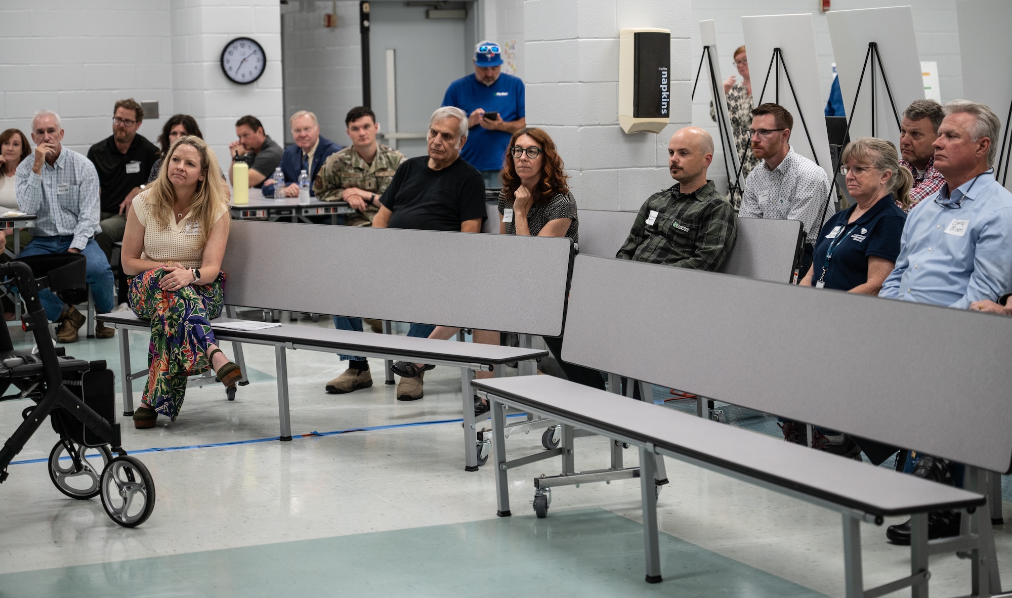 People sit on bleachers and listen intently.