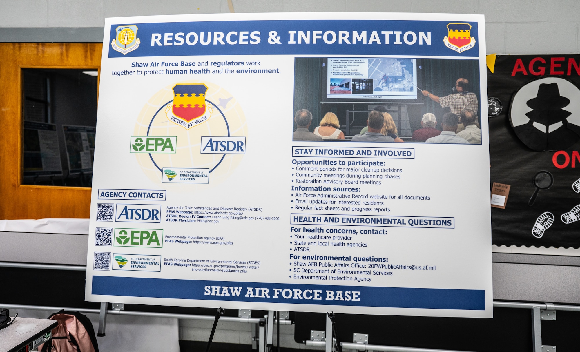A visual aid board with resources and information is displayed in a room.