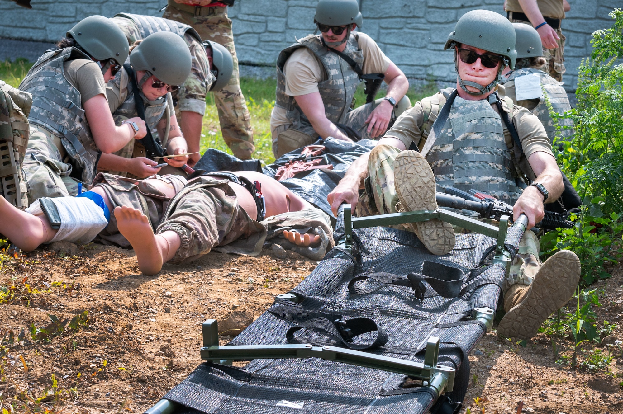 a person kicks a litter bar into place as others in render aid to simulated casualties